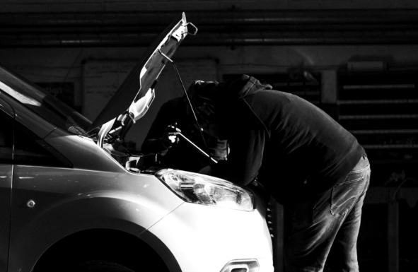 Mechanic with vehicle bonnet up carrying out servicing