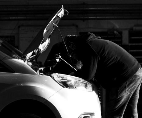 Mechanic with vehicle bonnet up carrying out servicing